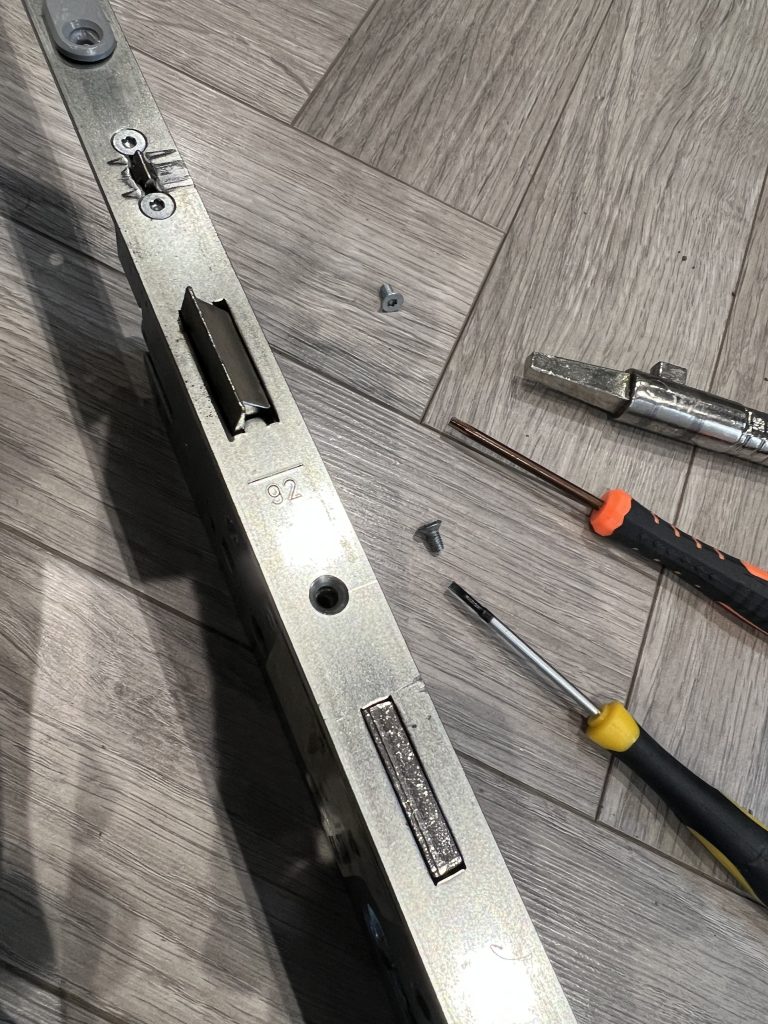 Closeup of a multipoint lock gearbox with tools.